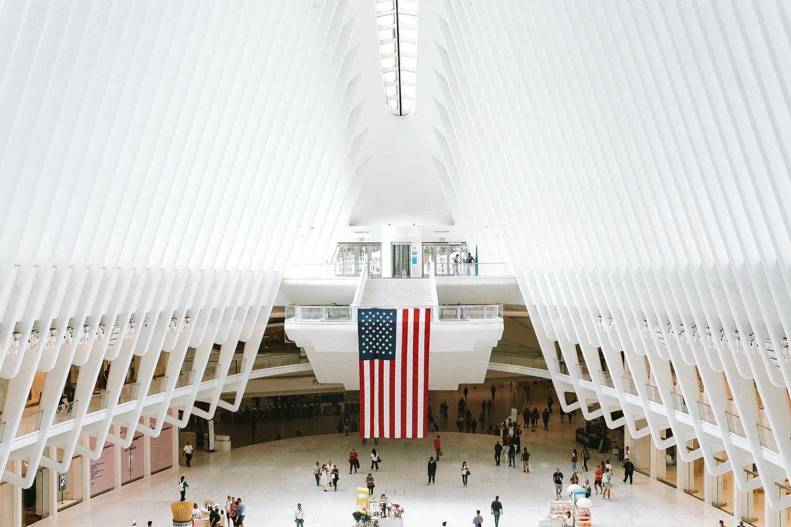 A breathtaking view of the Oculus in New York City, showcasing its iconic architecture with a prominent American flag.
